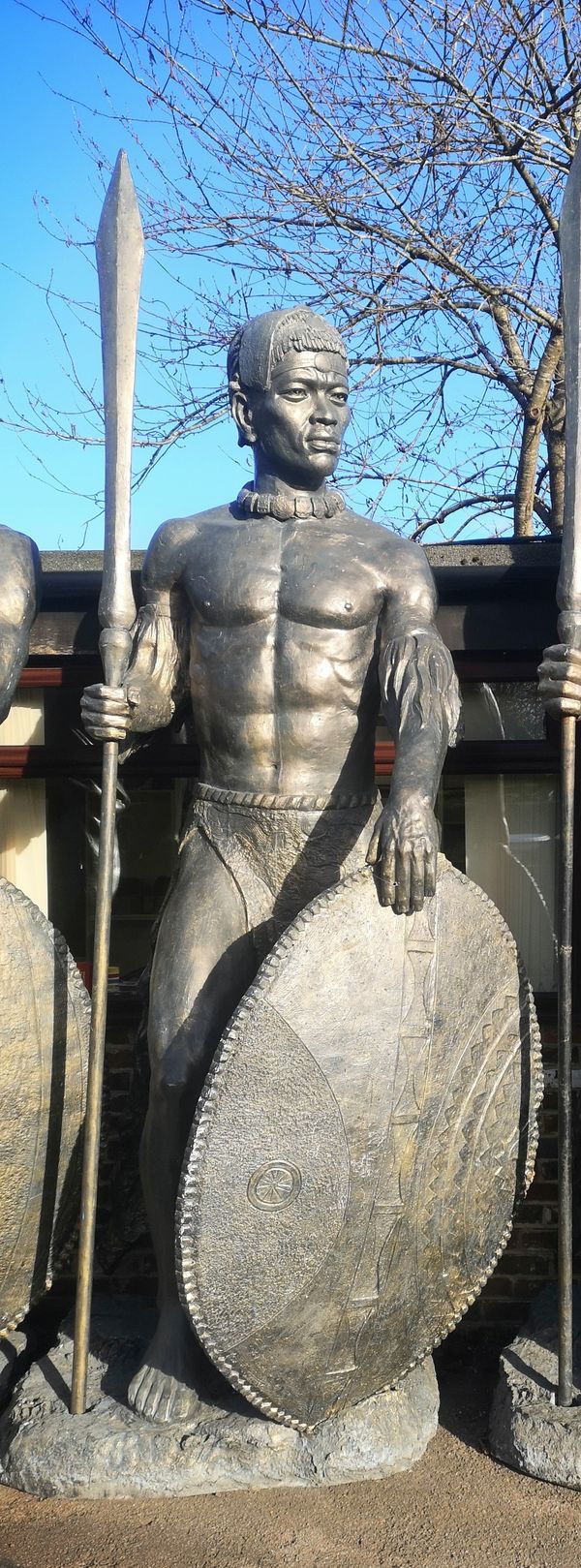 A similar impressive and colossal patinated fibreglass figure of a Zulu warrior