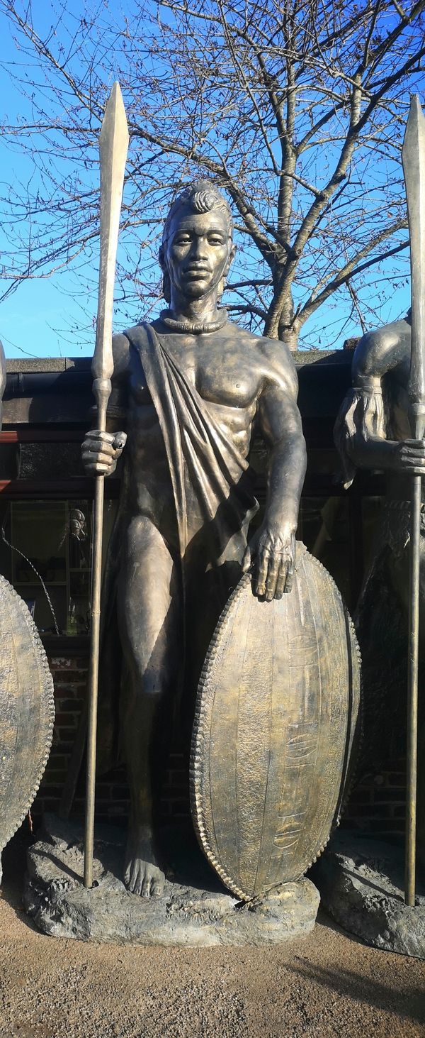 A similar impressive and colossal patinated fibreglass figure of a Zulu warrior