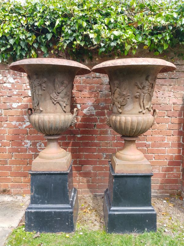 A pair of cast iron urns on pedestals
