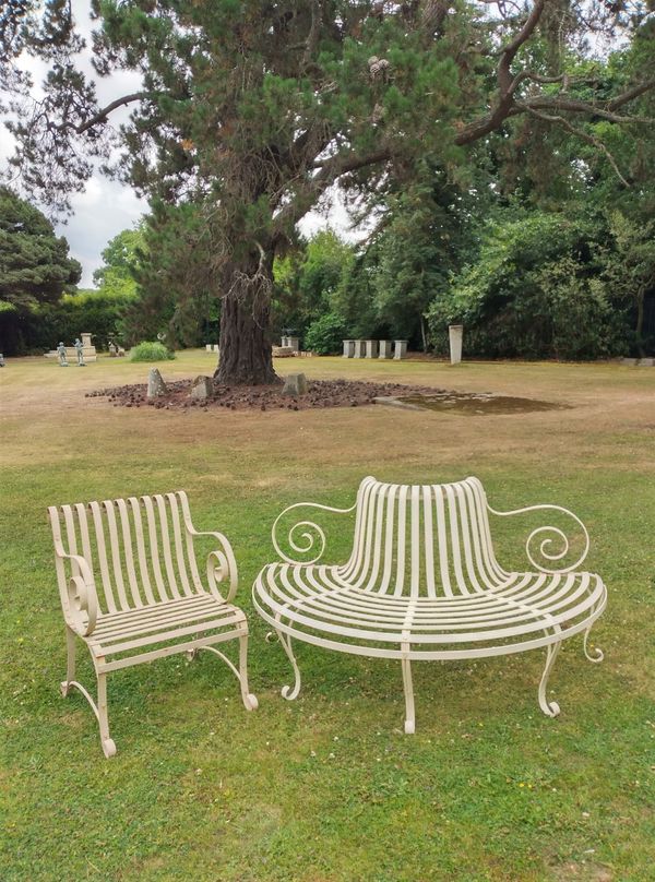 A wrought iron strapwork demi lune seat together with a similar chair