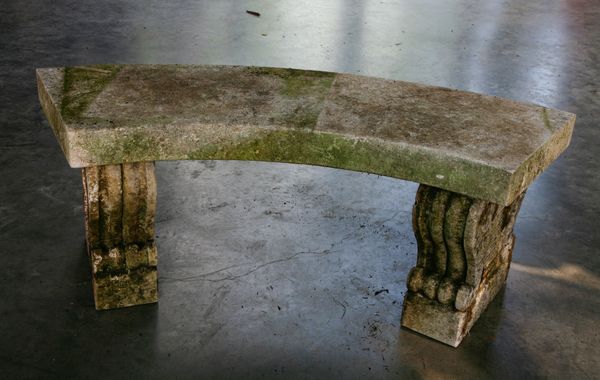 A curved limestone garden bench